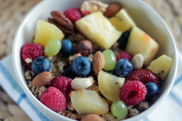 Colorful bowl of fresh fruit, berries, nuts and granola on a table