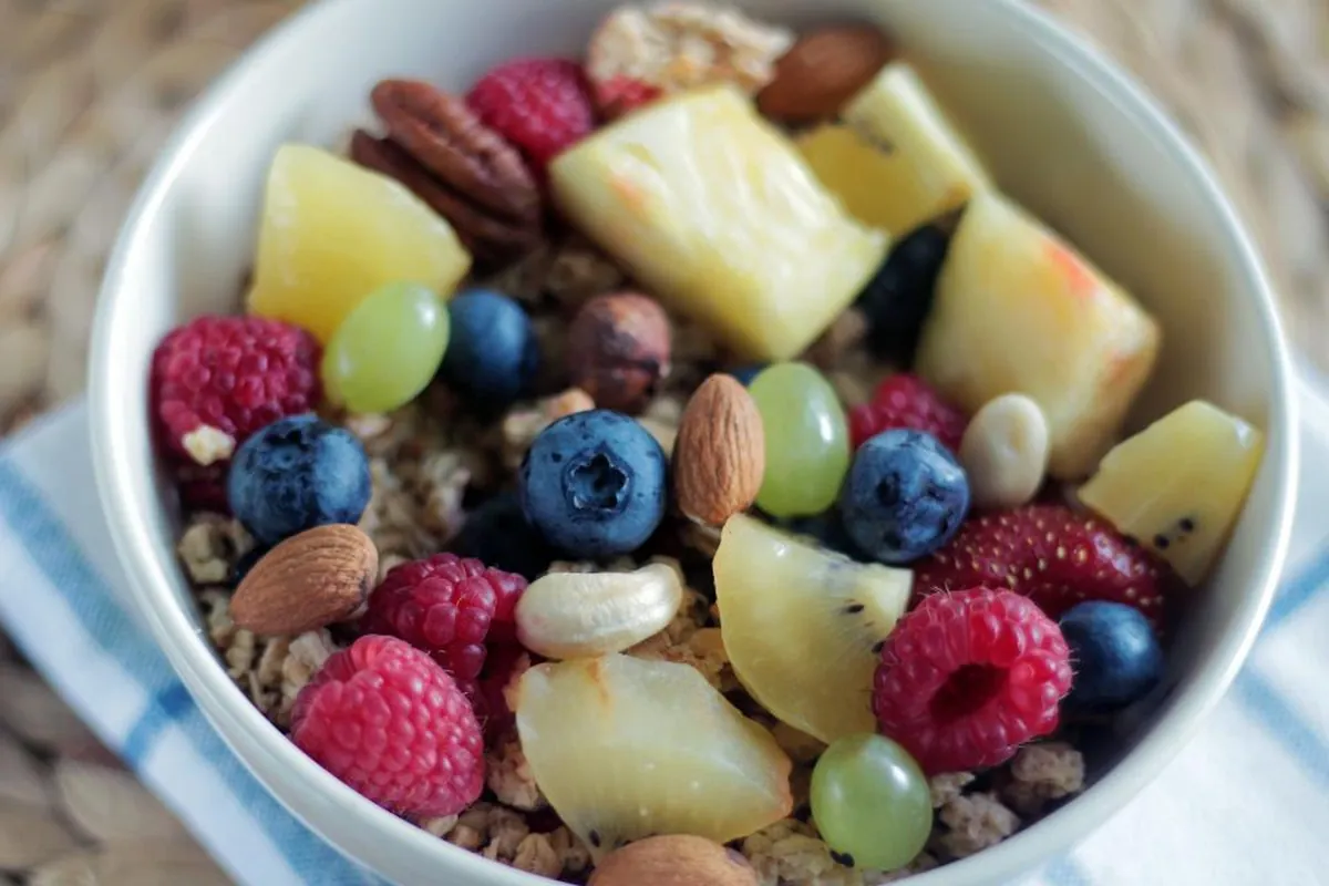 Colorful bowl of fresh fruit, berries, nuts and granola on a table