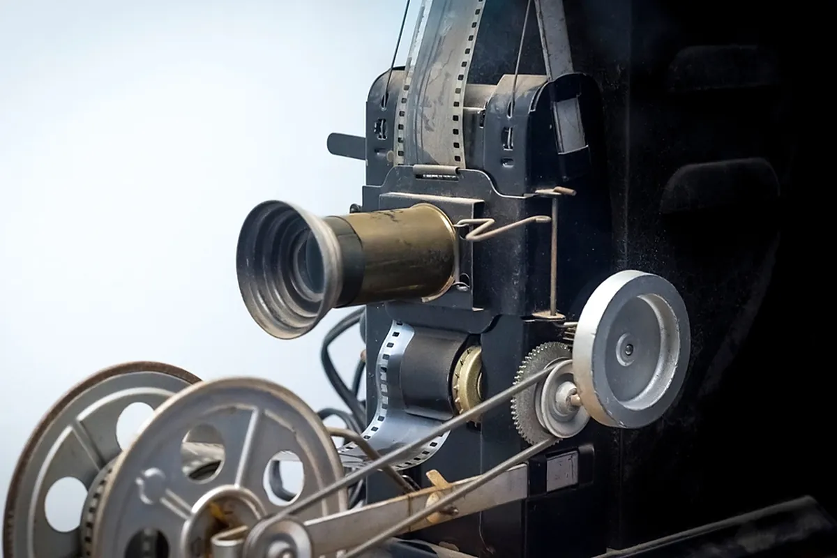 Classic film projector with large reels lit against a bright studio background